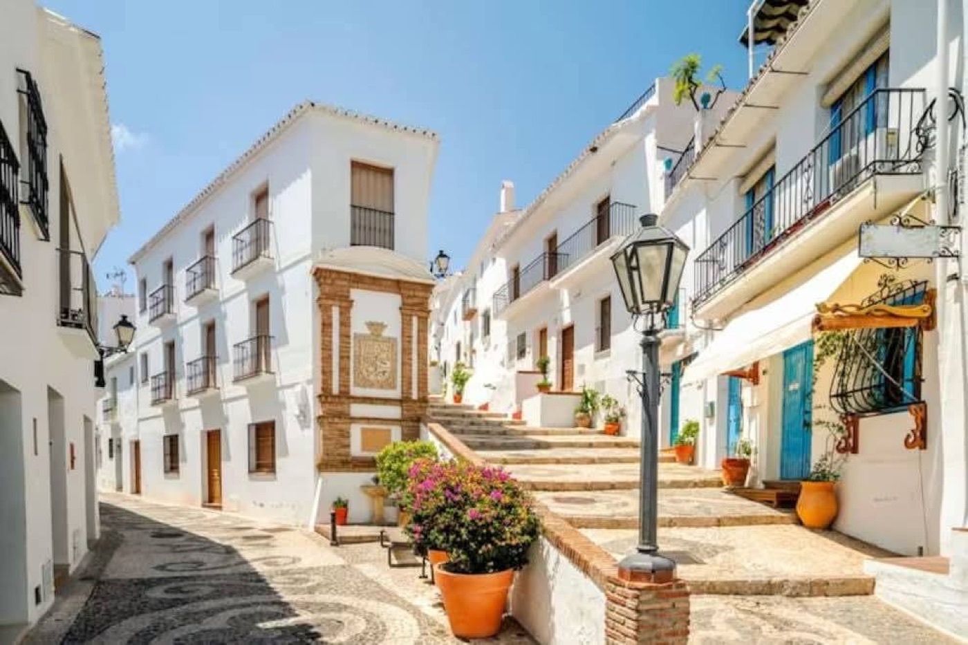 Calle blanca de Frigiliana con balcones y macetas