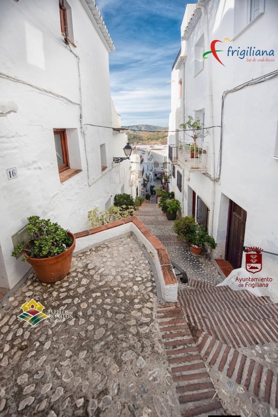 Callejón empedrado con escaleras y casas blancas de Frigiliana